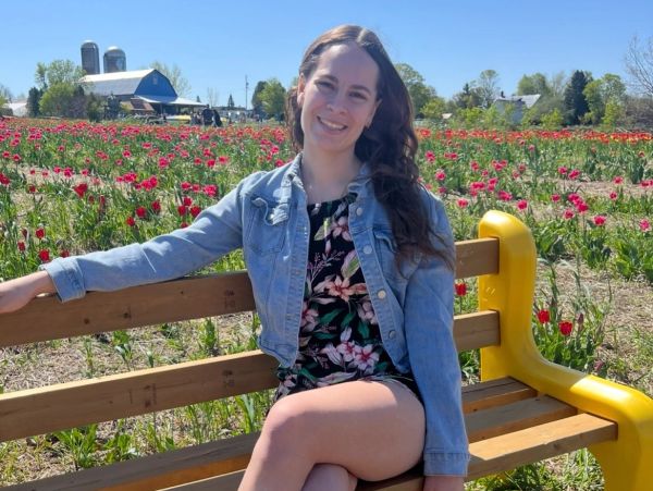 Woman sitting on a bench in a flower field.