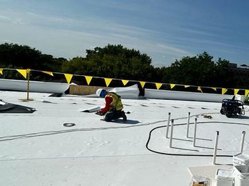 Trabajador en tejado aplicando material impermeabilizante.