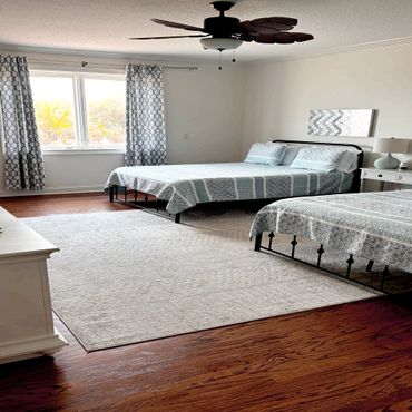 Cozy bedroom with two beds, patterned curtains, and wooden flooring.