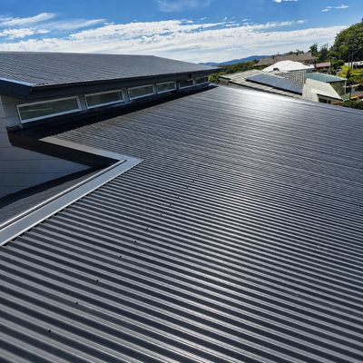 Modern black corrugated metal roof under blue sky.