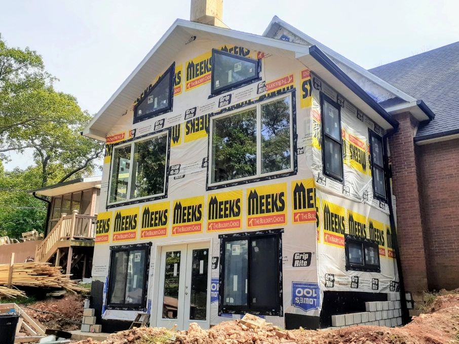 New house extension under construction with Meeks building wrap and multiple windows installed.