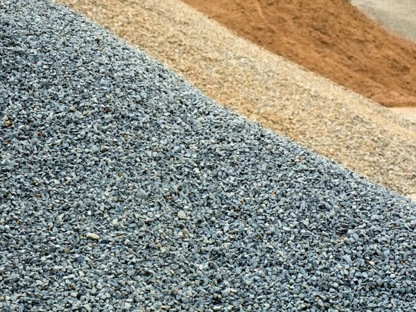 Three distinct piles of gravel and sand arranged in layers.