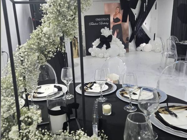 Elegant black and white birthday party setup with floral decor and balloons.