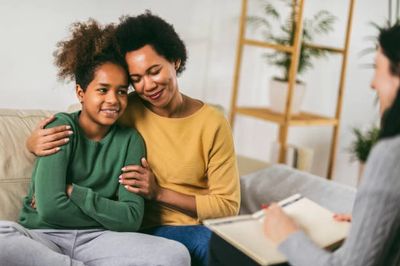 Mother brings daughter for child therapy and is comforting her daughter during an adolescent counseling session.