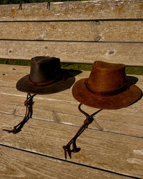 Two leather hats on a wooden bench.