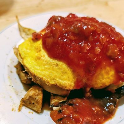 Toast topped with egg, lean protein, and chunky salsa on a white plate. A high‑protein breakfast.