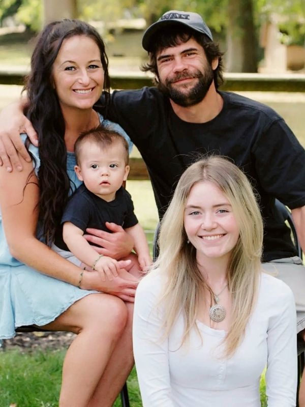 A happy family with a baby sitting outdoors on chairs.
