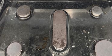 A slightly dirty black Frigidaire gas stove with four burners.