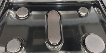 Top view of a clean black gas stove with five burners.