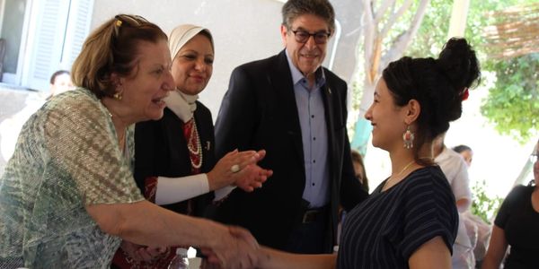 A woman participant of our Scholarship Program cheerfully shaking hands.