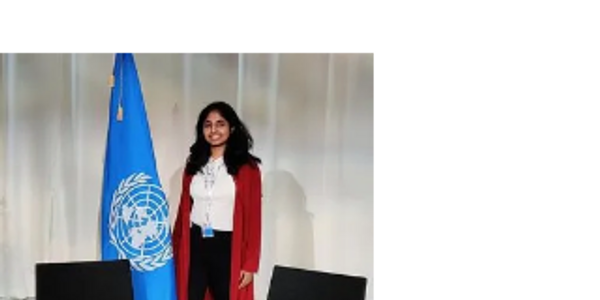 A smiling woman standing next to a United Nations flag