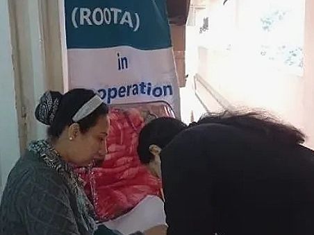 Women sitting in front of ROOTA sign.