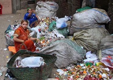 Two women sorting a trash pile on the ground