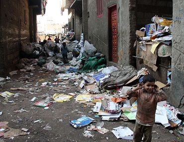 A boy standing in a street littered with trash