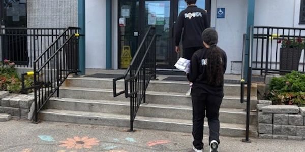 Two people walking into a building entrance with colorful chalk art on the ground.