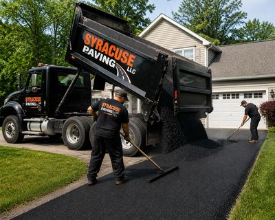 Workers paving a driveway with asphalt from a Syracuse Paving truck.