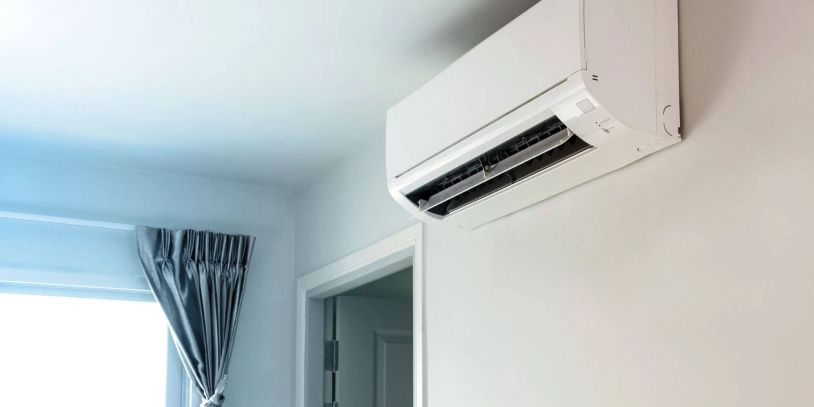 Wall-mounted air conditioner in a bright room with blue curtains.
