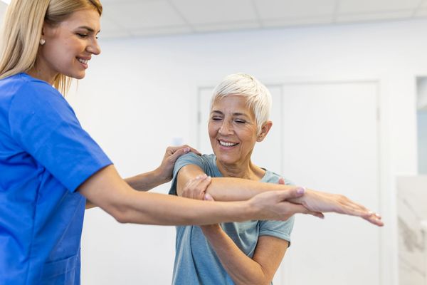 The image depicts two women in what appears to be a medical or rehabilitation setting.