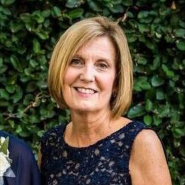 Smiling woman with short blonde hair in a navy lace dress.