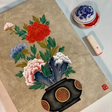 Traditional painting of colorful flowers in a black vase with ornate patterns.