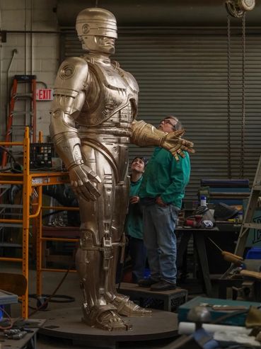 Finishing touches on the 'Robocop' sculpture, in Detroit, showcasing expert metal craftsmanship.