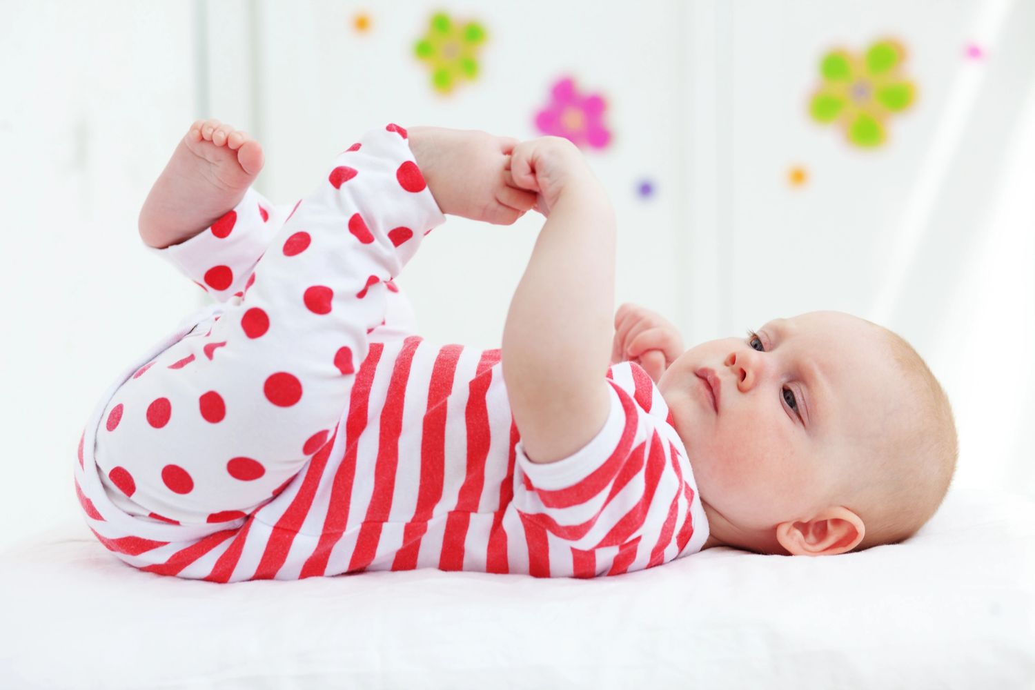 Baby wearing baby clothes with white and red stripes and dots