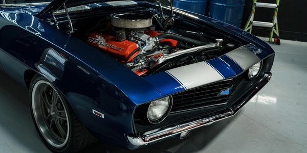 Classic blue muscle car with exposed engine and racing stripes.