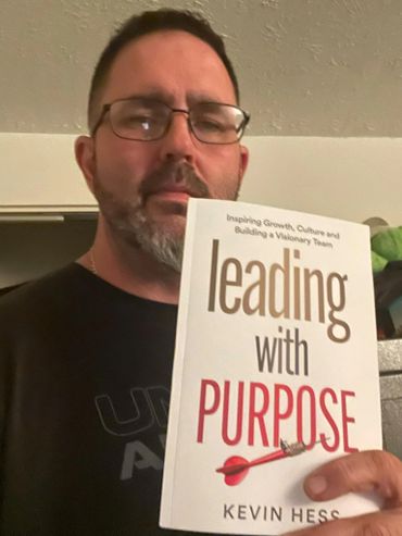 Man holding the book "Leading with Purpose" by Kevin Hess.