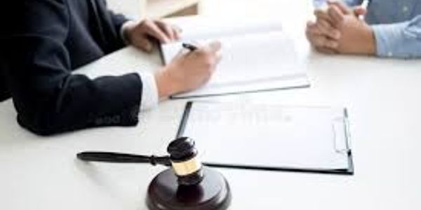 Two people discussing legal documents with a judge's gavel on the table.