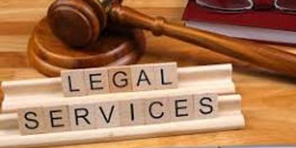 Wooden gavel and scrabble tiles spelling 'LEGAL SERVICES' on a desk.