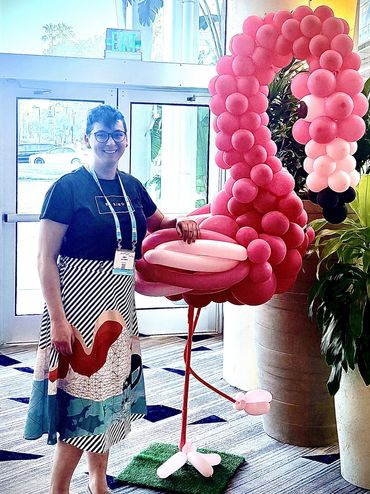 Therapist standing near a balloon sculpture of a flamingo.