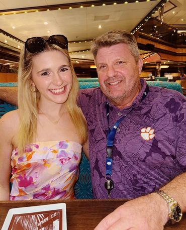 A smiling young woman and an older man sitting closely in a restaurant.