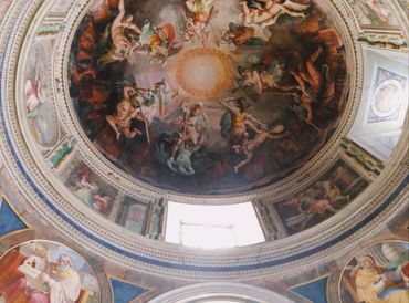 Intricate Renaissance frescoes adorn a grand domed ceiling with mythological figures and angels.