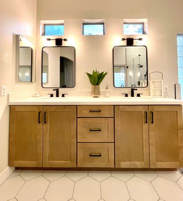 bathroom with two mirrors and wooden cabinets installed