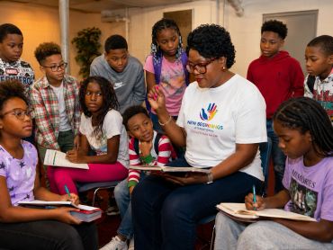 Teacher reading to a group of attentive children in a classroom.