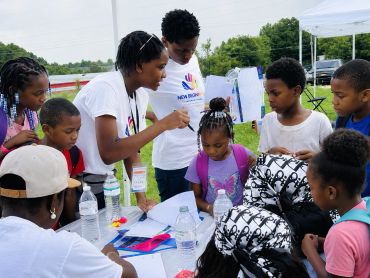 Children and staff engaging at an outdoor event table.