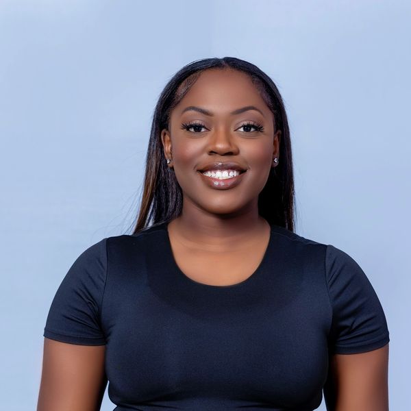Smiling woman in black top against light blue background.