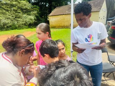 A woman teaches a group of children outdoors.
