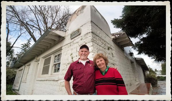 Two smiling people stand in front of the Adobe Gallery building.