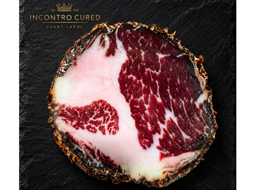 Close-up of a slice of cured meat with marbled fat.
