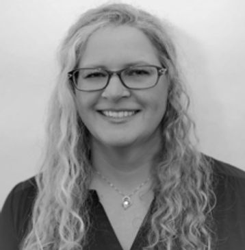 Smiling woman with glasses and curly blonde hair.