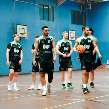 Basketball players in black jerseys walking on the court during a game.
