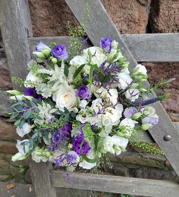 Hand tied bridal bouquet made up of white roses, astilbe, and spray roses and Purple lisianthus and