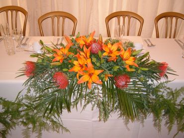 orange lily top table wedding arrangement by Arabella's flowers