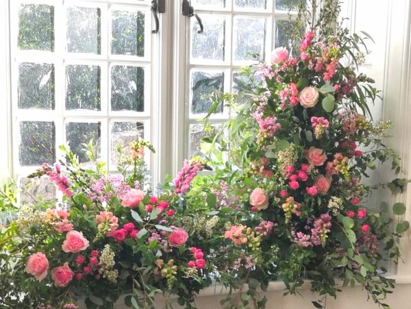 Wedding window arrangement of pink roses, pink spray roses and snapdragons
