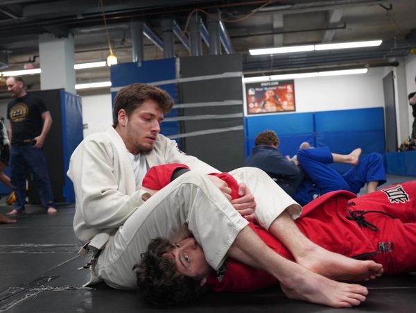 gym members wearing Brazilian jiu jitsu gi's work on an armbar submission together