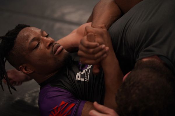 two gym teammates work together on the ground to perfect a submission