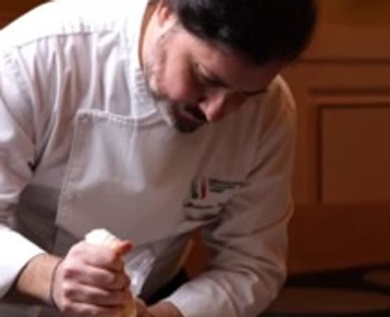 Chef decorating desserts with precision in a warm-lit kitchen.
