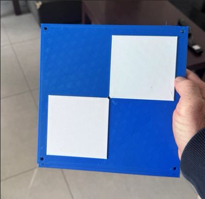Hand holding a blue board with two blank white squares.