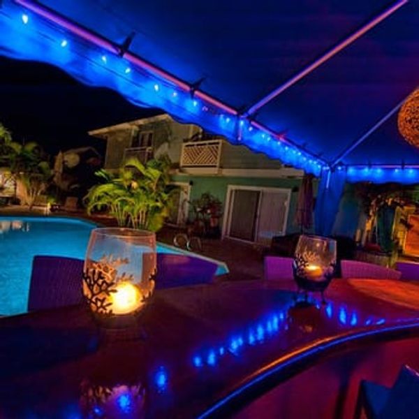 Nighttime poolside bar with blue lights and warm candle glow.